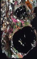 Cross-polarized light image of garnet-kyanite schist from New England. The large black minerals are garnets riddled with inclusions of quartz and plagioclase.