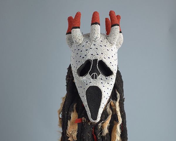 A ceremonial mask made of beads with a white face and horns