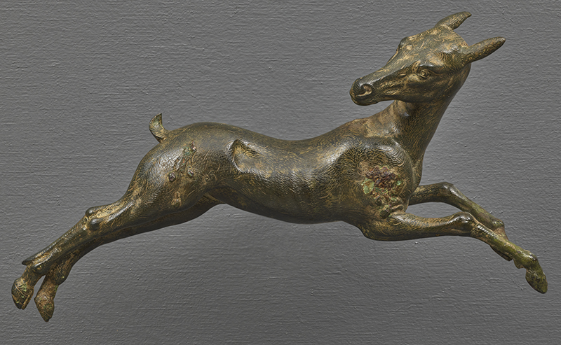 An ancient bronze sculpture of a leaping deer with head turned