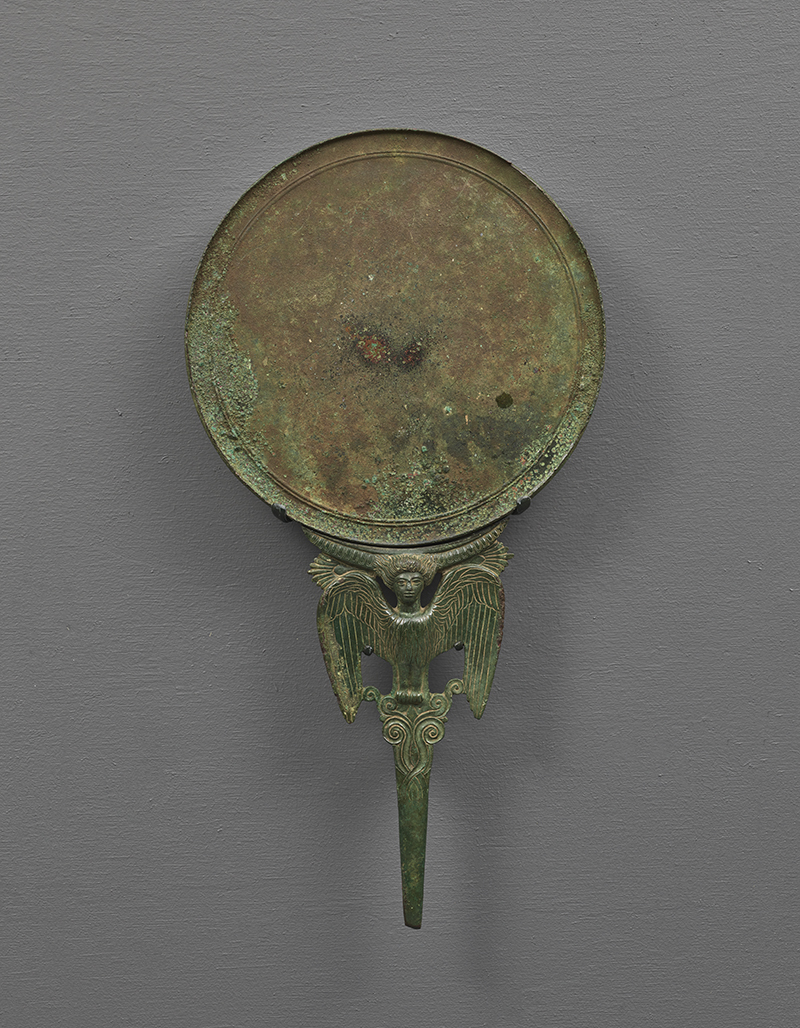 An ancient bronze mirror with a  siren, a mythological female figure decorating the handle