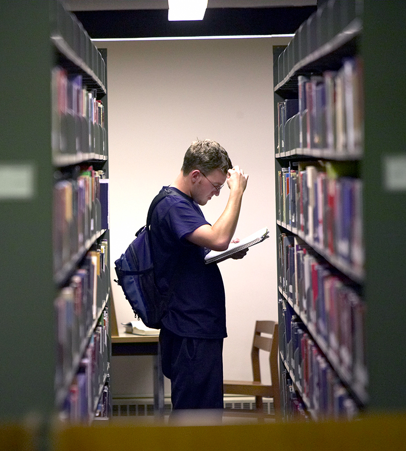 A student searches in the library stacks.