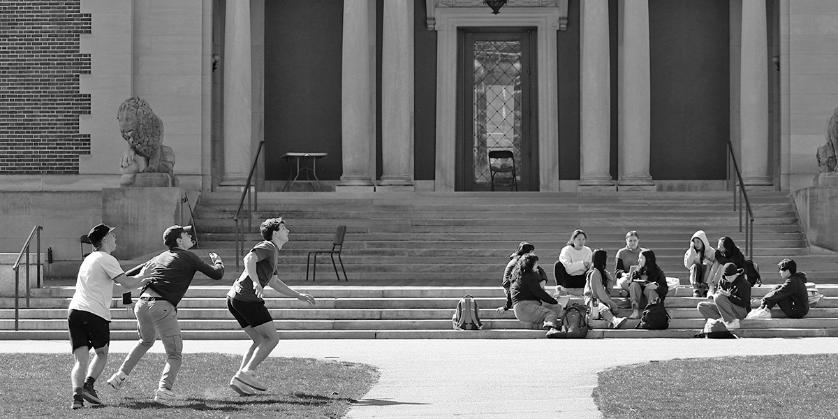 Bowdoin students toss a football in front of the steps of the Art Museum.