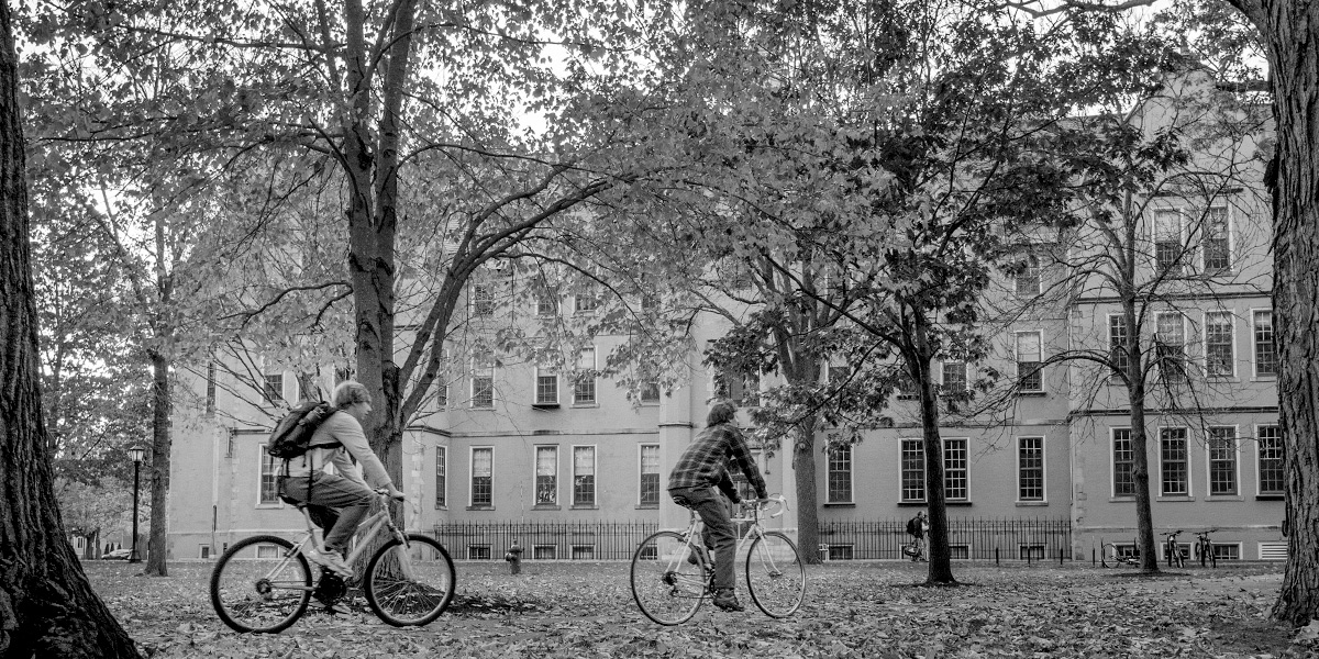 Bowdoin students bike through fall leaves on the Quad.