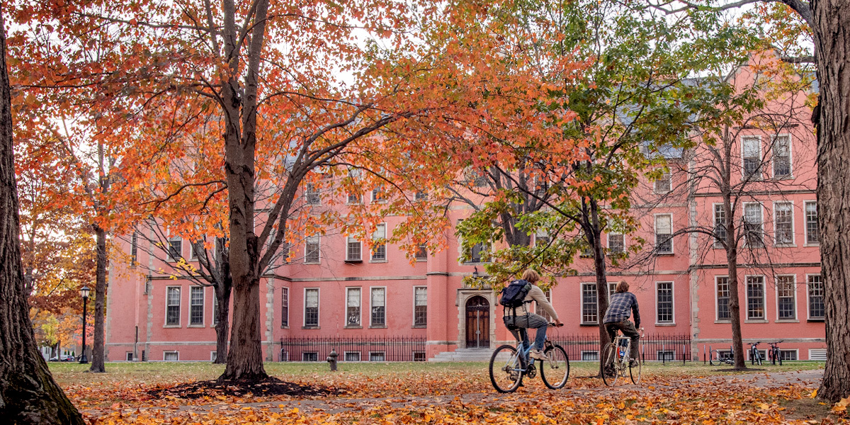 Bowdoin students bike through fall leaves on the Quad.