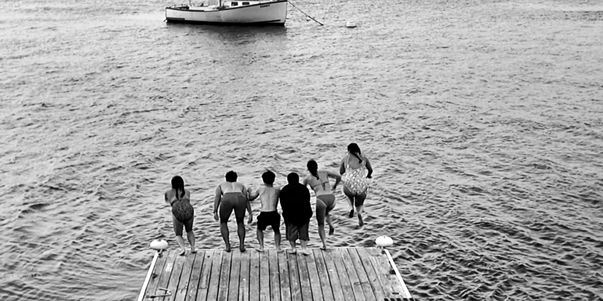 New Bowdoin students jump from a dock on an Orientation trip.