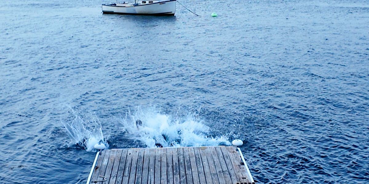 New Bowdoin students jump from a dock on an Orientation trip.