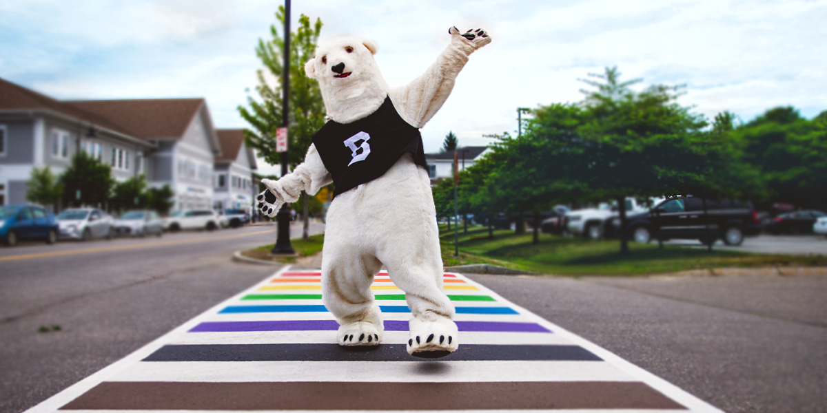The Bowdoin Polar Bear crosses a PRIDE-painted crosswalk in downtown Brunswick.