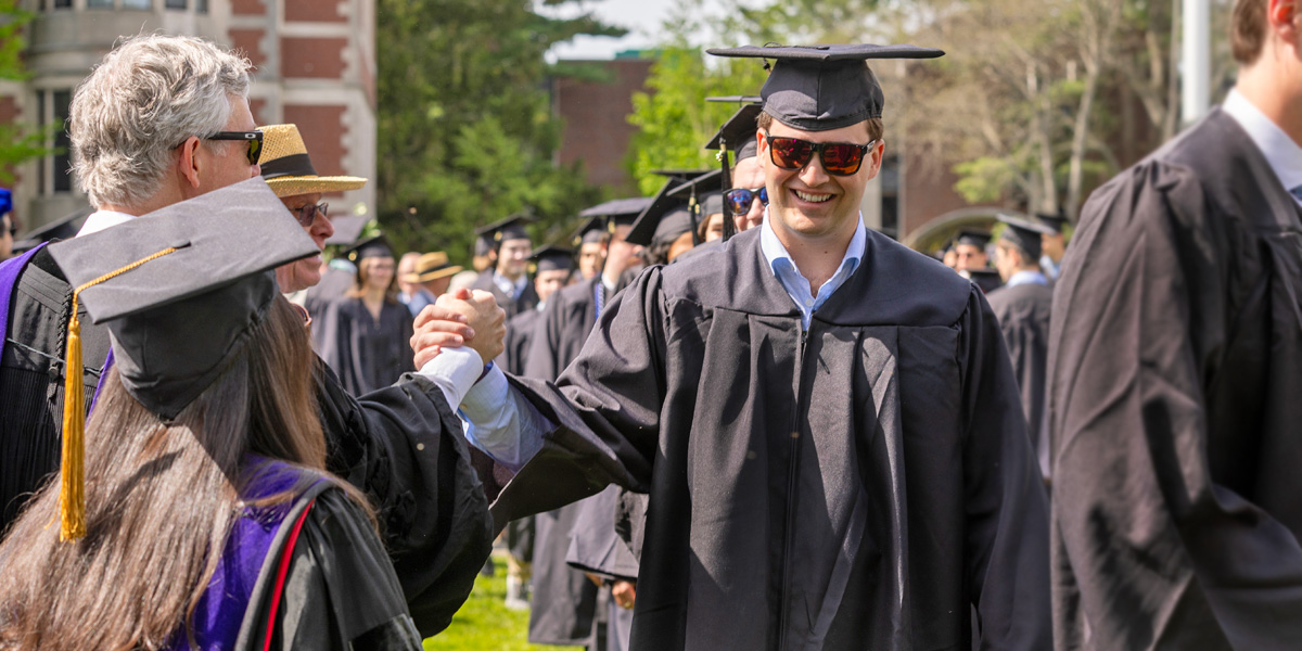 Bowdoin graduates greet faculty in line at Commencement.