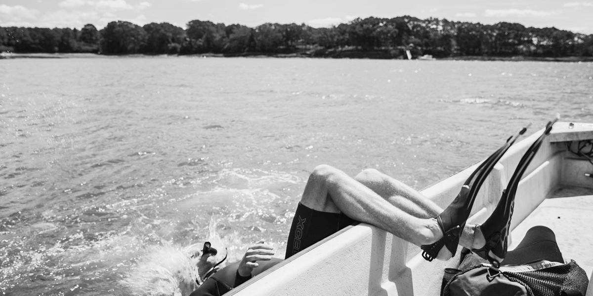 A SCUBA diver flips backwards off of the boat