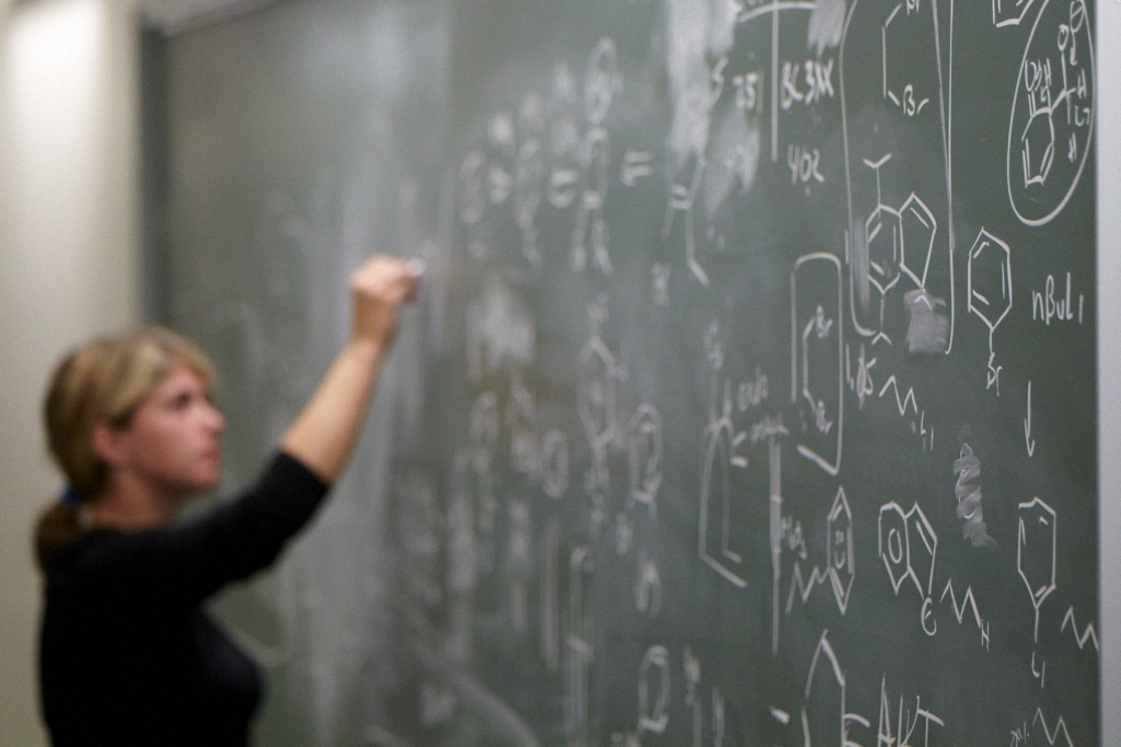 A student works on chemistry at the chalkboard.