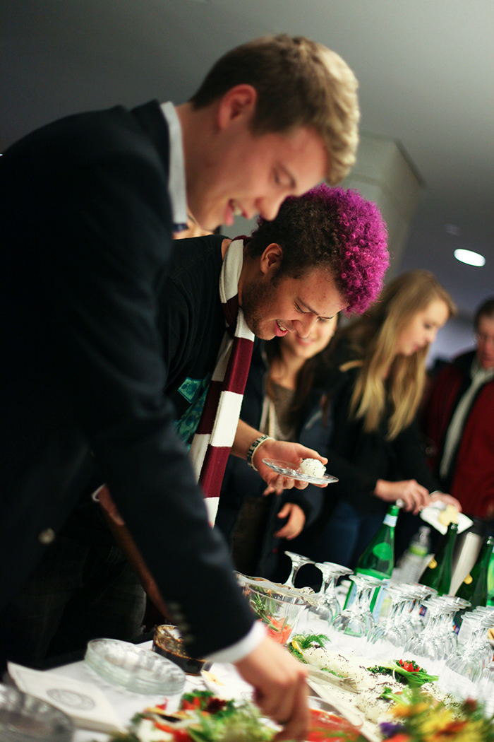 A group of students picking up refreshments off of a reception table