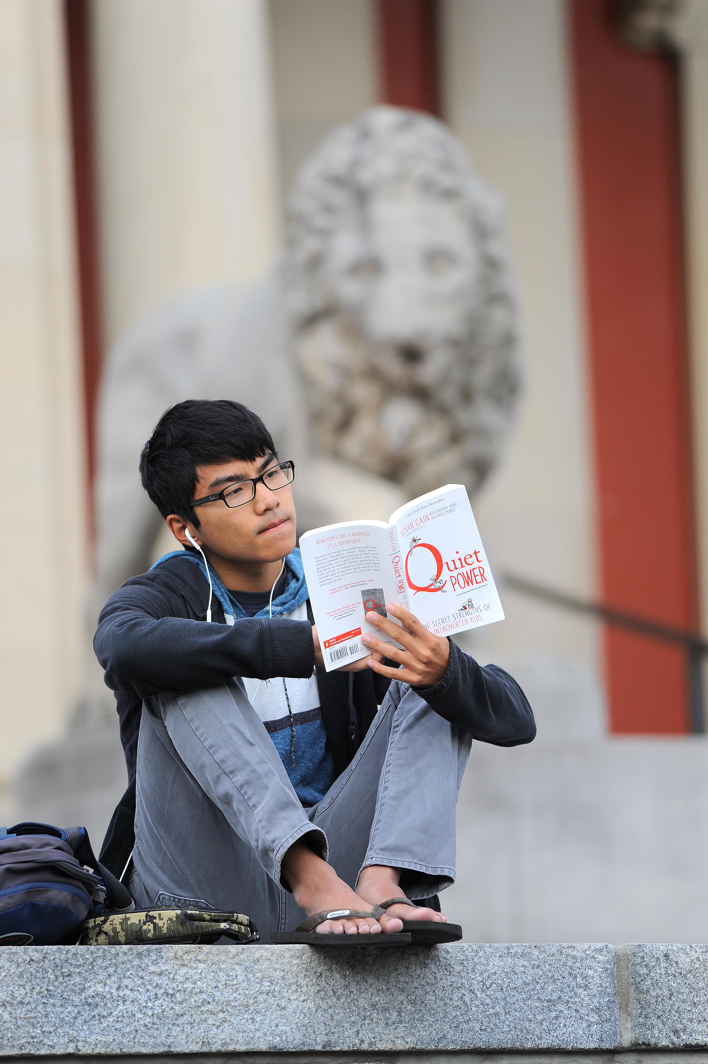 A student reads in front of the Museum of Art