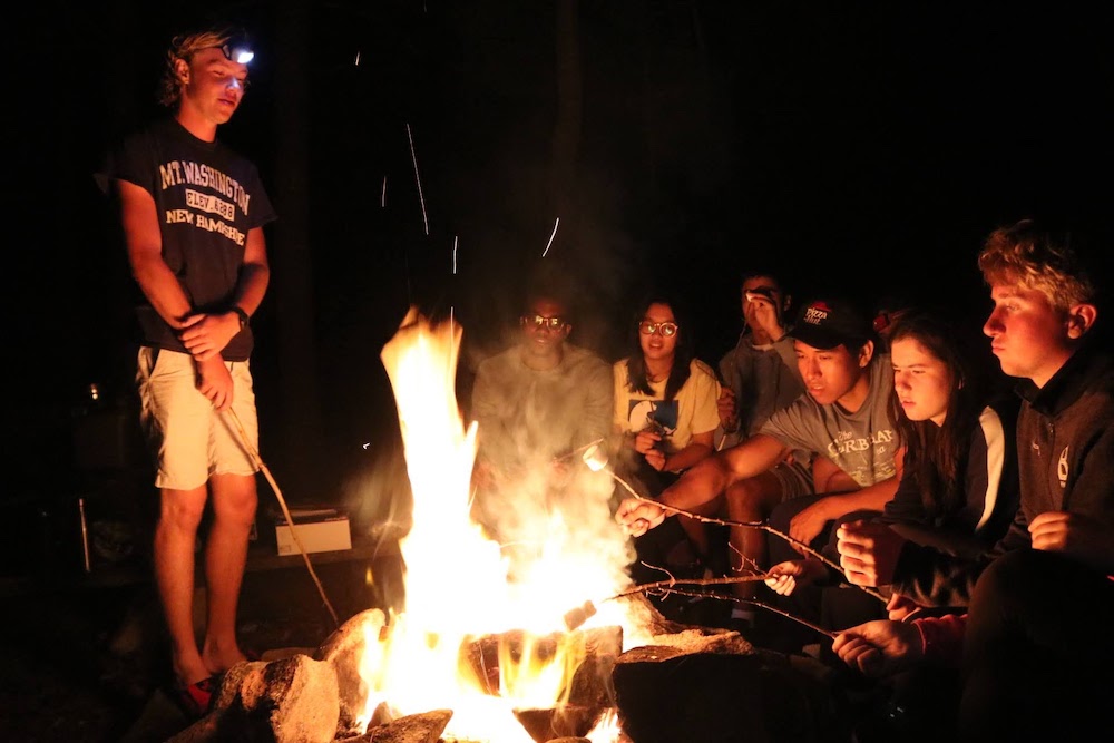 Students roasting smores around a campfire