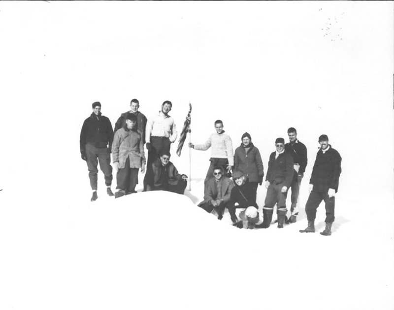<p><b>Boys at Farthest North </b> </p>   In 1948, during the <em>Bowdoin's</em> 16th expedition, favorable ice conditions allowed MacMillan to sail the schooner to its farthest north ever, only 11° from the North Pole. Although very strong, the  <em>Bowdoin</em> was not designed to break thick ice. The crew worked the ship through pack ice with someone in the ice bucket calling directions to the person at the wheel. Solid ice, such as the crew stands on here, signaled an end to any further progress.  <br /> <br />   Donald B. MacMillan. Boys at farthest north: l-r, Paul Eitel, Al Barnes, Peter Rand (behind), Bill Deutsch, George Webster, Nate Corning (holding flag), Stanton Cook, Miriam MacMillan, Bruce Nelson (in front), John Snyder, Cliff Ives (behind), James Wiles. Kane Basin, 1948. Silver gelatin print. Gift of Donald and Miriam MacMillan.