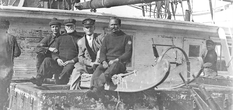 Four men on sledge on ROOSEVELT. Donald Baxter MacMillan far left, Matthew A. Henson far right.