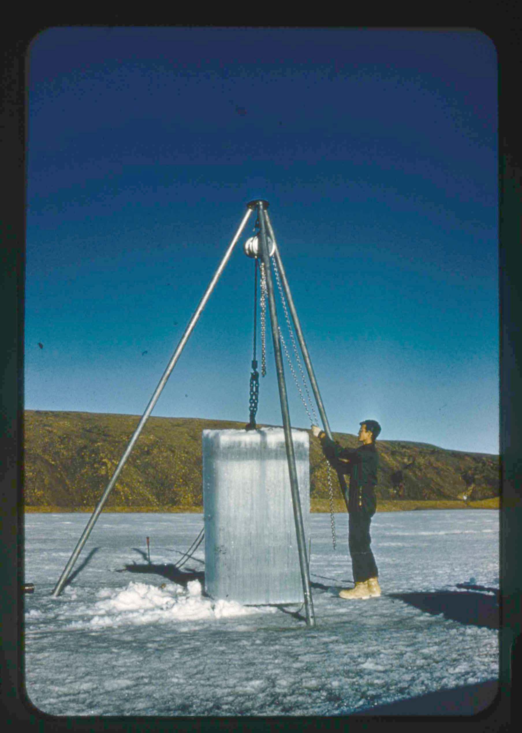 Stanley Needleman, Cabaniss Removing Block of Ice Cut from Lake for Strength Tests, Lake Peters, northwest Greenland, August 1, 1956. 35mm slide. Gift of Stanley Needleman.