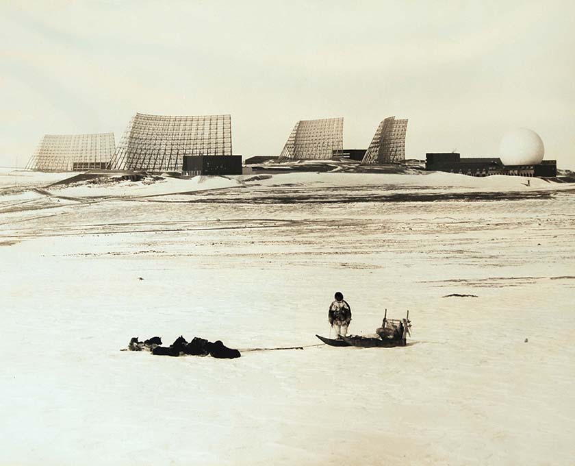 View of Ballistic Missile Early Warning System (BMEWS) with Inughuit man and sledge in foreground, 