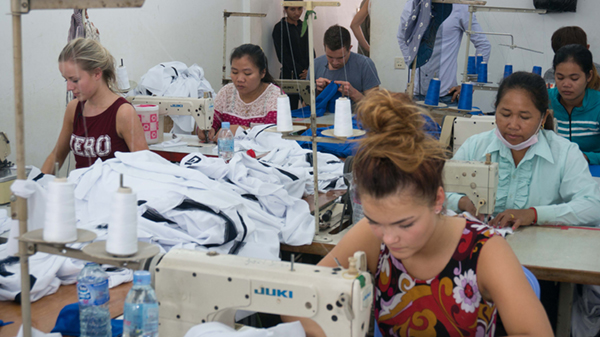 A group of women in a factory, sewing intentlly