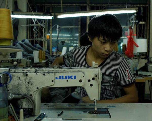 A man working in a factory sewing a garment