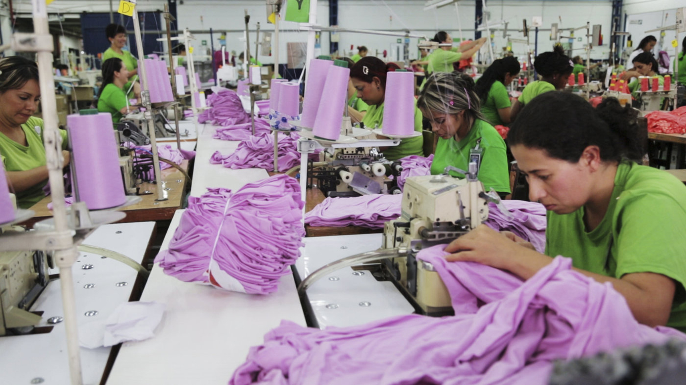 A photo of workers in a clothing factory making pink t-shirts
