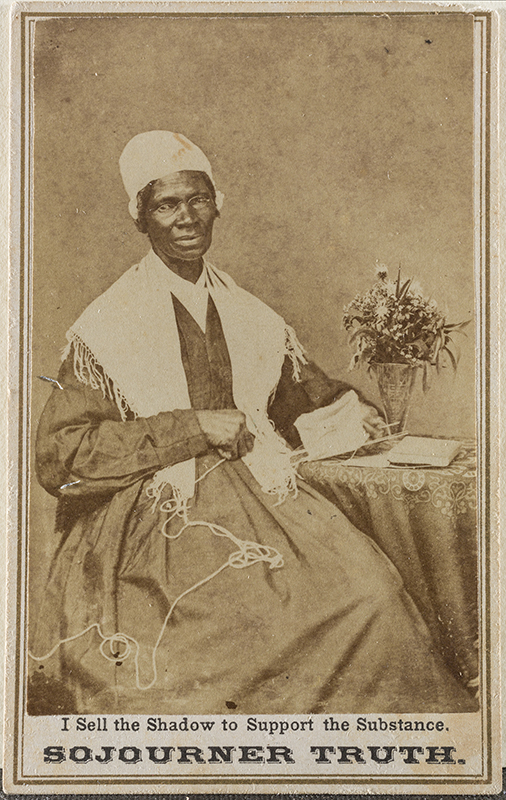 a sepia photograph showing a seated woman in a shawl in a long dress