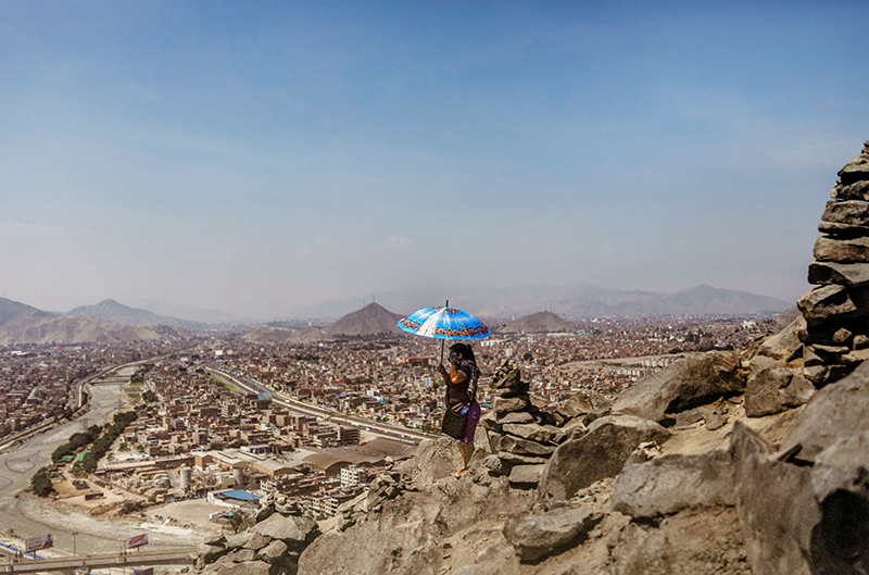 a photograph of a rocky landscape, with a cityscape in the distance, and a person holding an umbrella