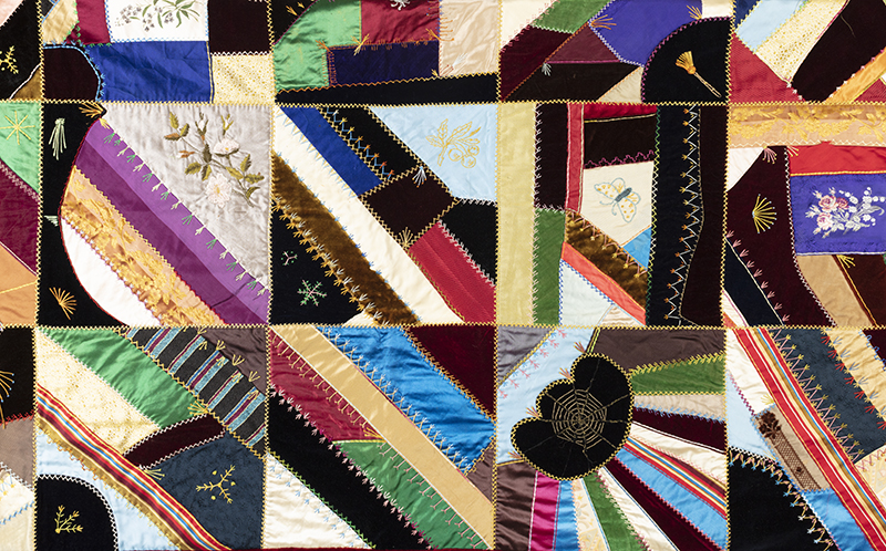 an embroidered quilt in rich colors with fancy needlework