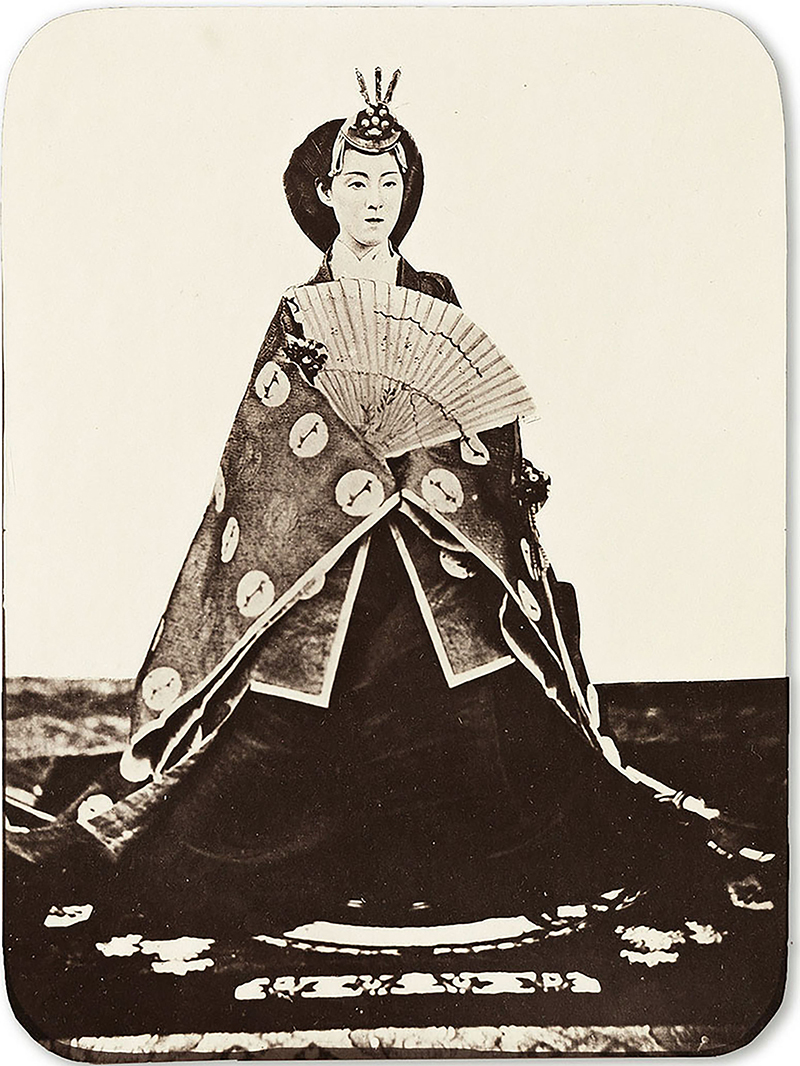 a sepia photograph showing a woman in a long dress holding a fan
