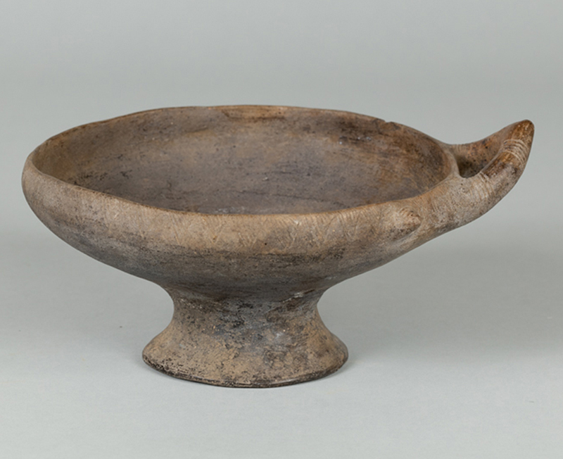 An ancient, dusty-colored clay, stem-footed bowl 