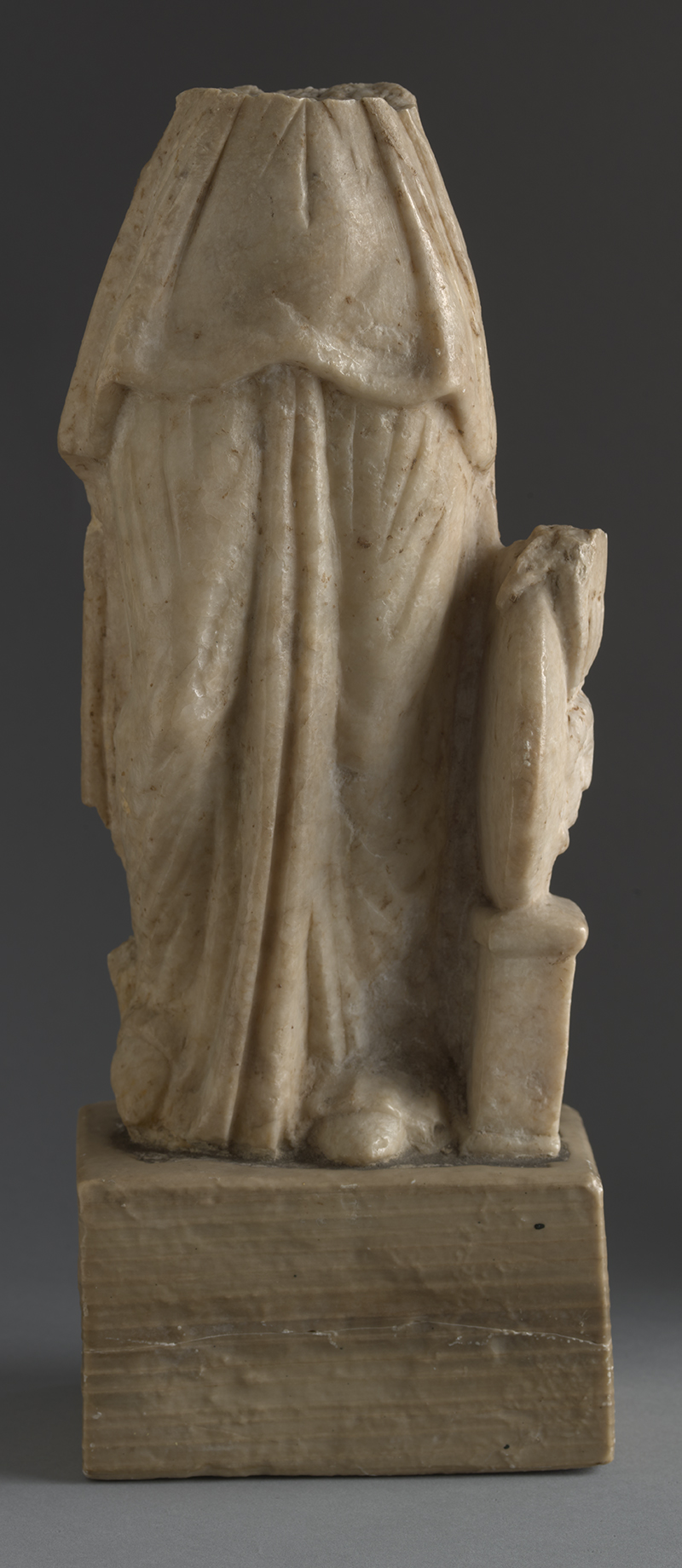 a partial statue of a draped figure made of stone