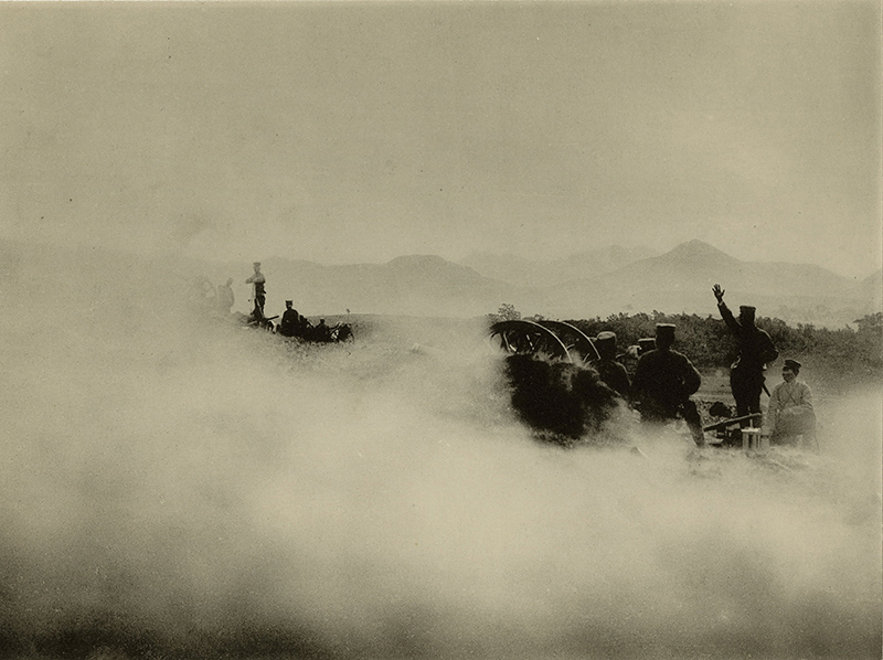 Sepia photo of a smoke filled field with soldiers and a cannon