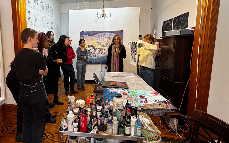 People gather in an artist's studio to look at colorful artwork