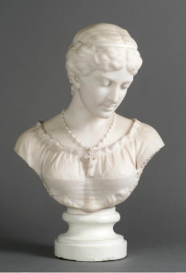bust of woman gazing downward. Her hair is pulled back and she wears a necklace with cross pendent 