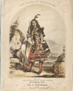a person in native attire leans on a stick in front of rocks