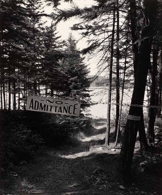 A black and white photograph shows the words No Admittance and Private Property on a coastline