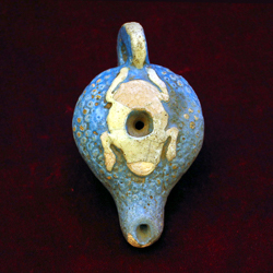 A small blue clay oil lamp with the silhouette of a frog