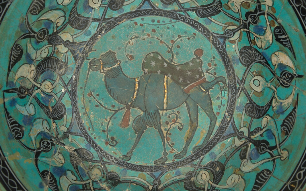 A detail of a turquiose Perisan bowl with the image of a camel and geometric designs