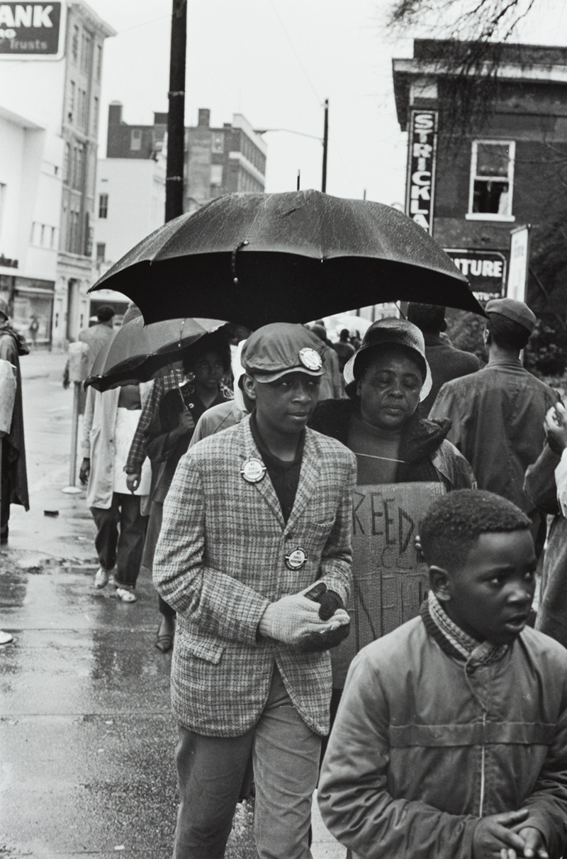 A photograph of  people on the street with umbrellas