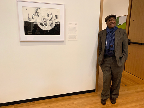 A photo of a gentleman leaning against a wall in an art gallery