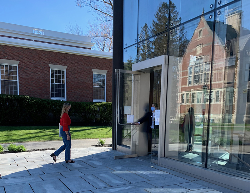 A woman walking towards a glass pavilion, the entrance to the Museum