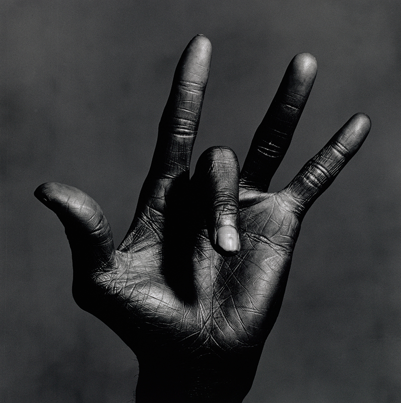 a black and white photo of a man's hand with four fingers extended