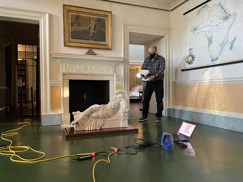 A man with a 3D scanner working with a marble sculpture
