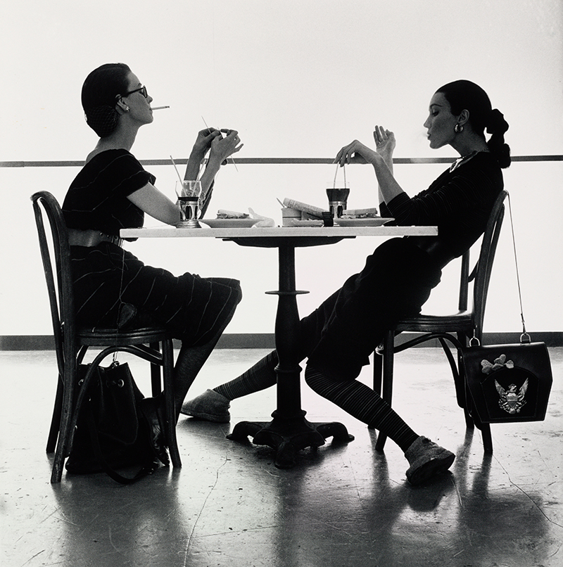 A black and white photo showing two women seated a table