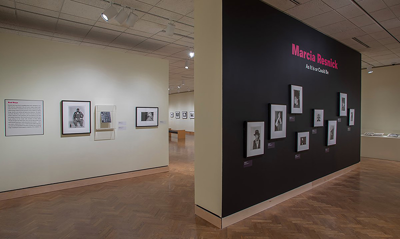 A gallery in an art museum with a title wall and small photogaphs