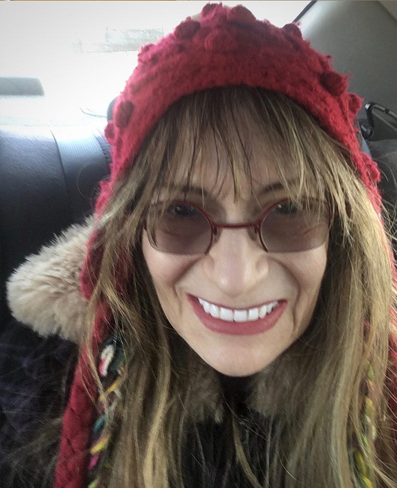 A close up photograph of a smiling woman in a red slouchy hat
