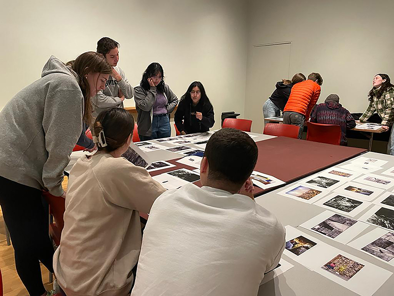 A group of people studying images laid out on a table