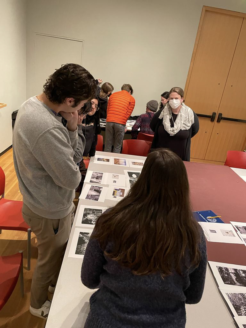 Students in a museum classroom, looking at pictures on a table