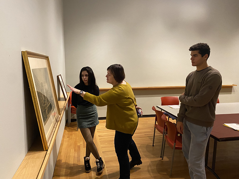 Three figures looking at a work of art, on gesturing toward the work