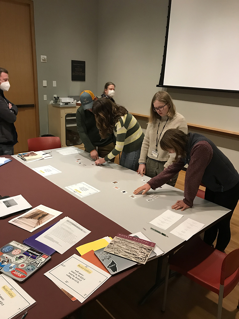 students around a table studying photographs and papers