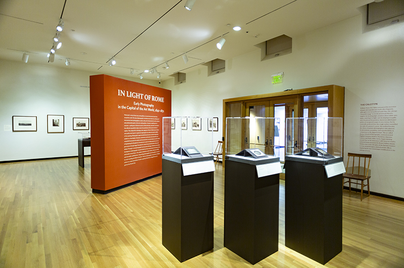 A gallery with art on the walls.  Three pedestals are in the foreground.